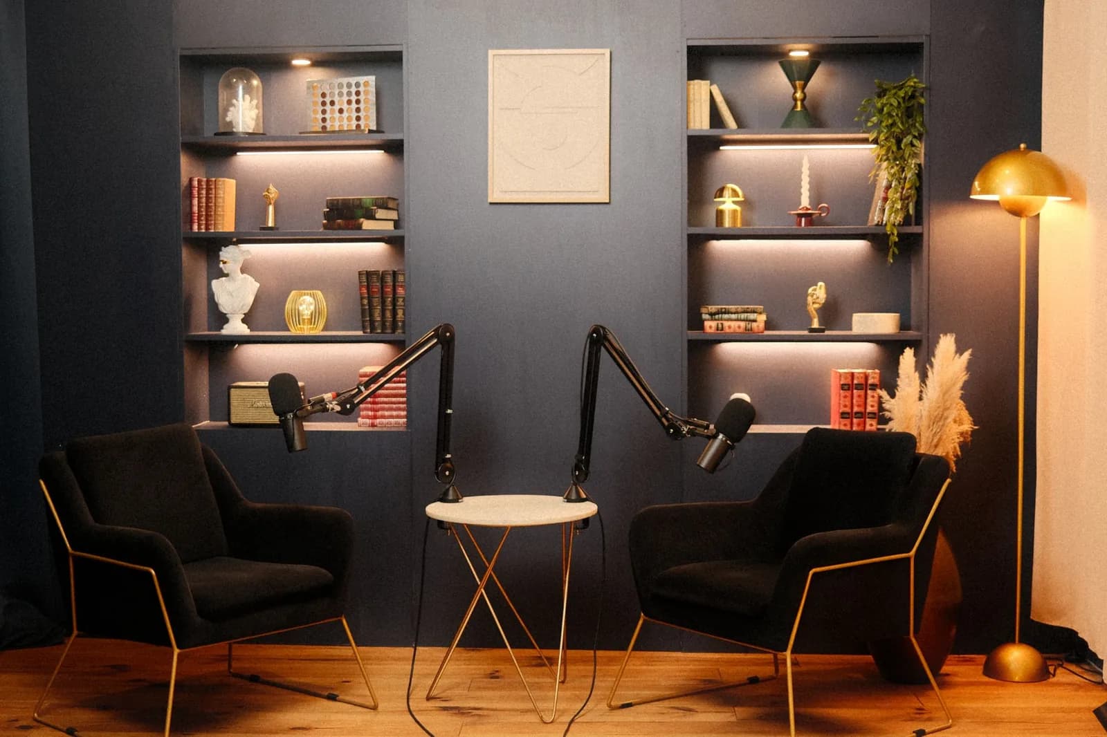 Décor Vénus du studio podcast KOSMOS à Bordeaux : bibliothèque bleu nuit, tableau et fauteuils en velours noir
